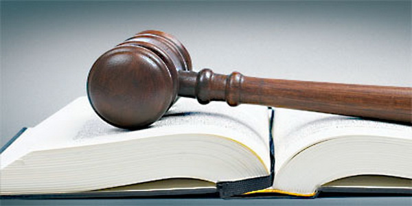 Wooden gavel from the court over the opened law book reflected on white background with space for text. Shallow DOF